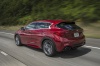 Driving 2019 Infiniti QX30S in Magnetic Red from a rear left three-quarter view